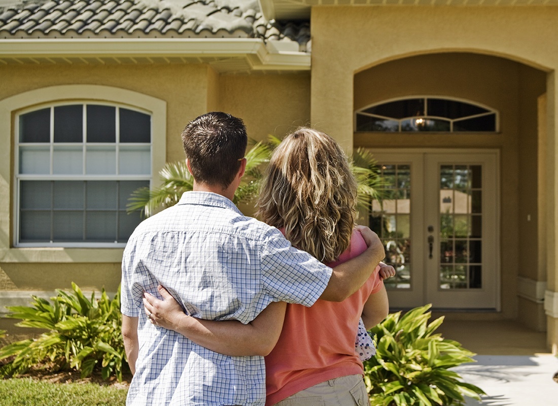 Contact - Rear View of a Young Married Couple Standing Outside Looking at Their New Home in Florida